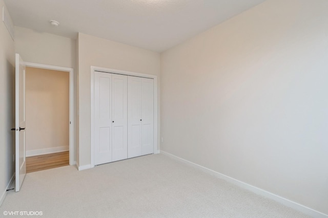 unfurnished bedroom with light colored carpet and a closet