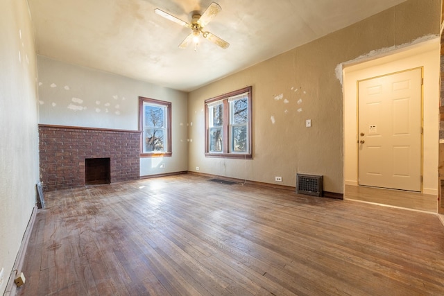 unfurnished living room with ceiling fan, wood-type flooring, a fireplace, and visible vents