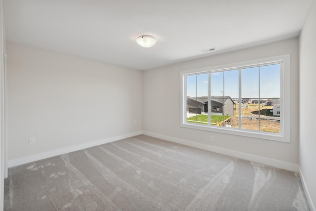 spare room featuring carpet, visible vents, and baseboards