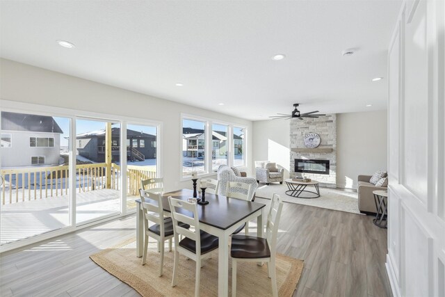 dining room with a fireplace, light wood-style flooring, and recessed lighting