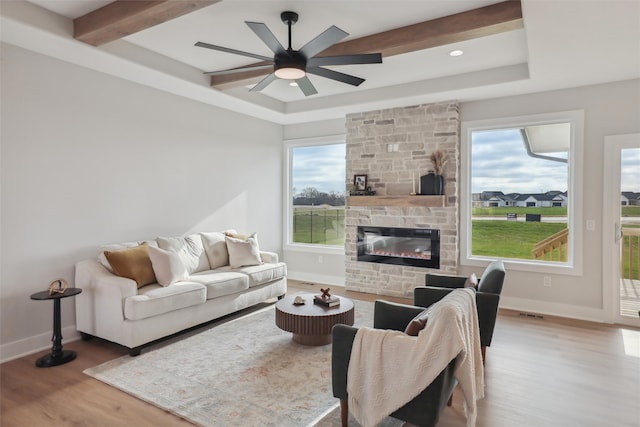 living room with hardwood / wood-style flooring, ceiling fan, beam ceiling, and a fireplace