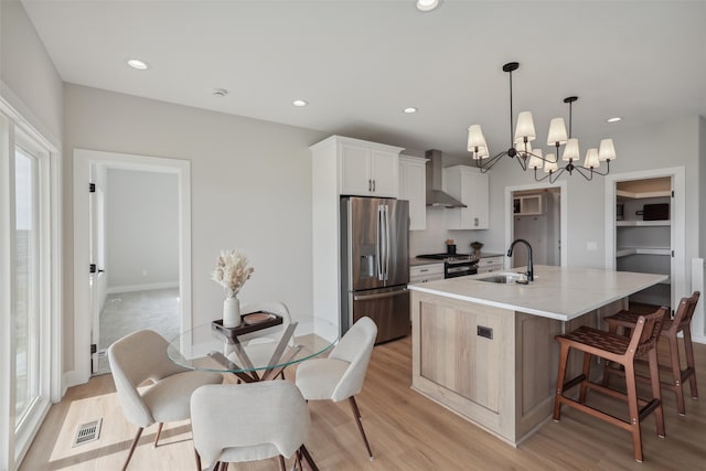 kitchen with a center island with sink, sink, appliances with stainless steel finishes, plenty of natural light, and white cabinetry