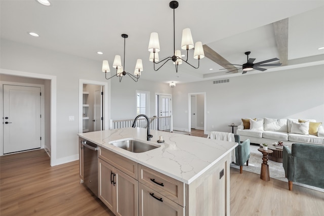 kitchen featuring stainless steel dishwasher, a kitchen island with sink, sink, decorative light fixtures, and light hardwood / wood-style flooring