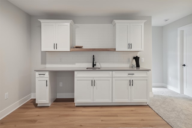 kitchen featuring decorative backsplash, white cabinetry, and sink