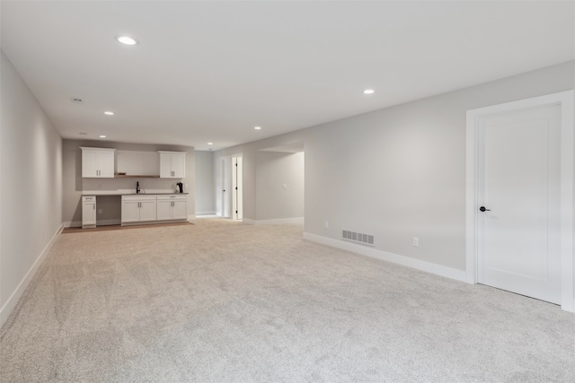 unfurnished living room with light colored carpet and sink