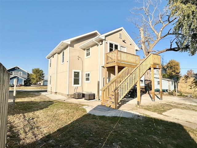 back of property with a wooden deck, central AC unit, a patio, and a lawn