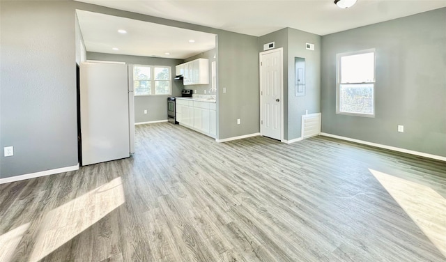 unfurnished living room featuring sink and light hardwood / wood-style floors