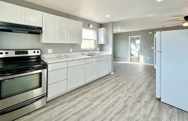 kitchen featuring stainless steel electric stove, white fridge, sink, and white cabinets