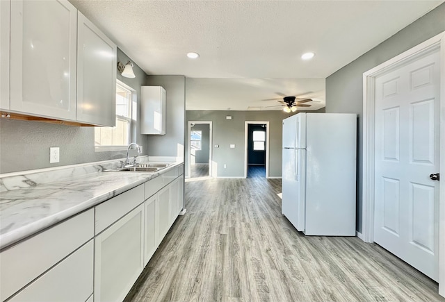 kitchen with white cabinets, ceiling fan, light hardwood / wood-style flooring, white fridge, and sink