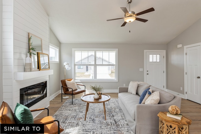 living room featuring hardwood / wood-style floors, vaulted ceiling, a large fireplace, and ceiling fan