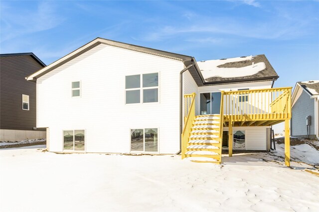 snow covered house featuring stairway and a wooden deck