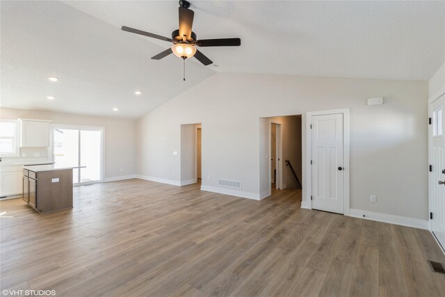 unfurnished living room featuring lofted ceiling, light wood-type flooring, visible vents, and baseboards