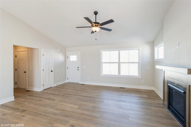 unfurnished living room featuring light wood-style floors, baseboards, a ceiling fan, and a glass covered fireplace