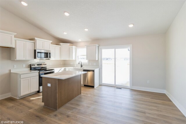 kitchen featuring stainless steel appliances, light countertops, light wood-style floors, white cabinetry, and a kitchen island