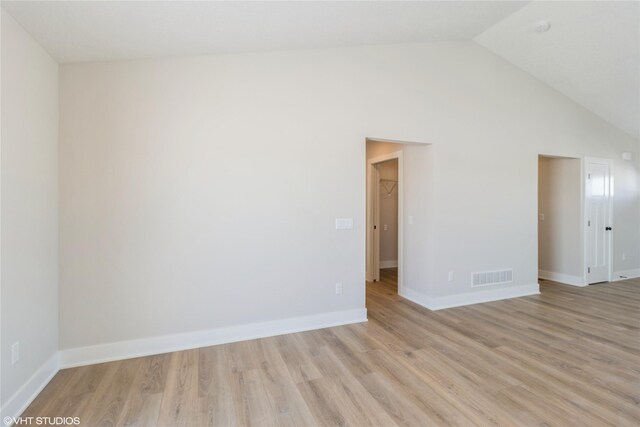 empty room featuring high vaulted ceiling, baseboards, visible vents, and light wood finished floors