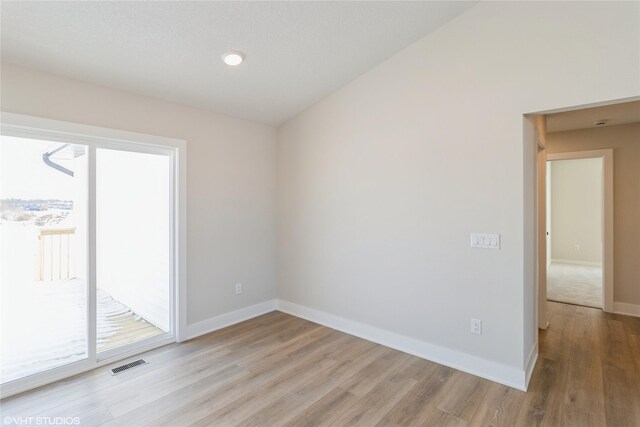 empty room featuring visible vents, light wood-style flooring, and baseboards