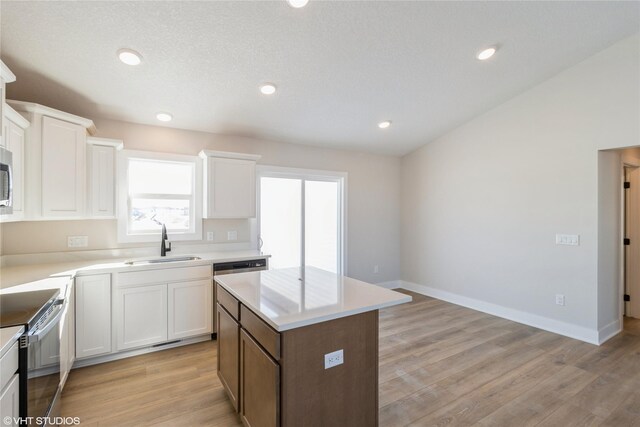 kitchen featuring a center island, light countertops, stainless steel range with electric cooktop, a sink, and white cabinetry