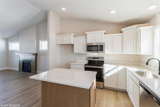 kitchen with appliances with stainless steel finishes, a center island, light countertops, and white cabinets