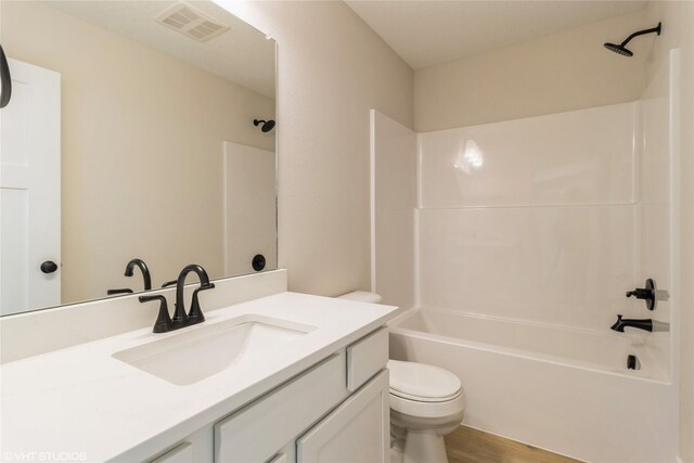 full bath with visible vents, toilet, vanity, shower / tub combination, and wood finished floors