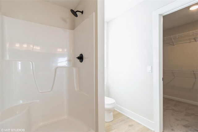 full bathroom featuring a walk in closet, toilet, and a shower stall