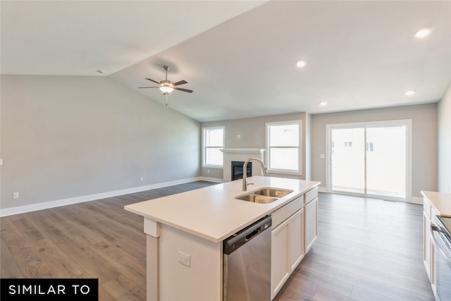 kitchen featuring an island with sink, appliances with stainless steel finishes, light wood-type flooring, vaulted ceiling, and sink