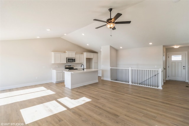 unfurnished living room with vaulted ceiling, ceiling fan, light hardwood / wood-style floors, and sink