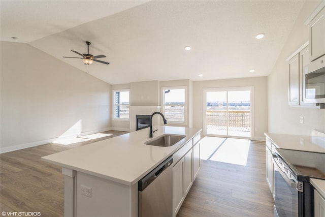 kitchen featuring sink, a kitchen island with sink, stainless steel appliances, white cabinets, and vaulted ceiling