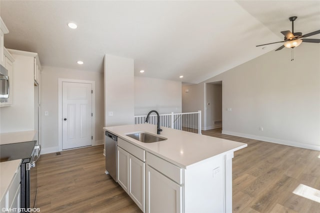 kitchen featuring appliances with stainless steel finishes, sink, white cabinets, a center island with sink, and light hardwood / wood-style flooring