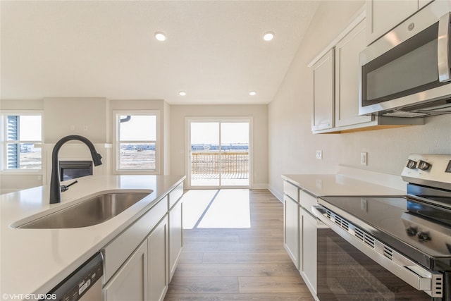 kitchen with white cabinetry, sink, light hardwood / wood-style flooring, and appliances with stainless steel finishes