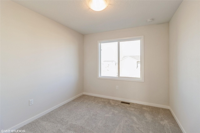 empty room featuring light colored carpet and a textured ceiling