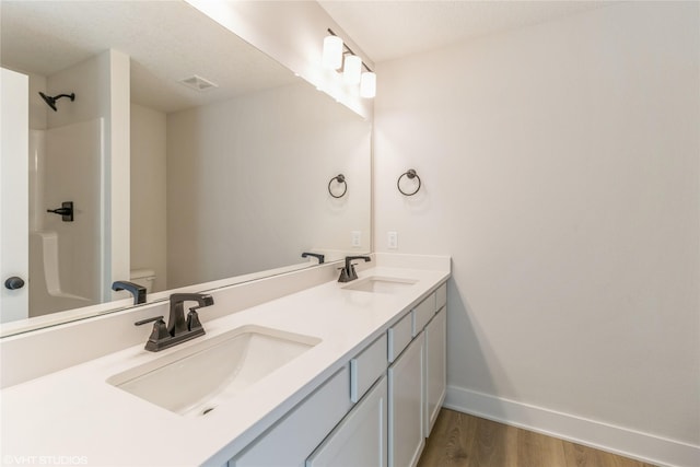 bathroom featuring vanity, hardwood / wood-style flooring, toilet, and walk in shower