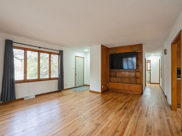 unfurnished living room with visible vents, baseboards, and light wood-type flooring