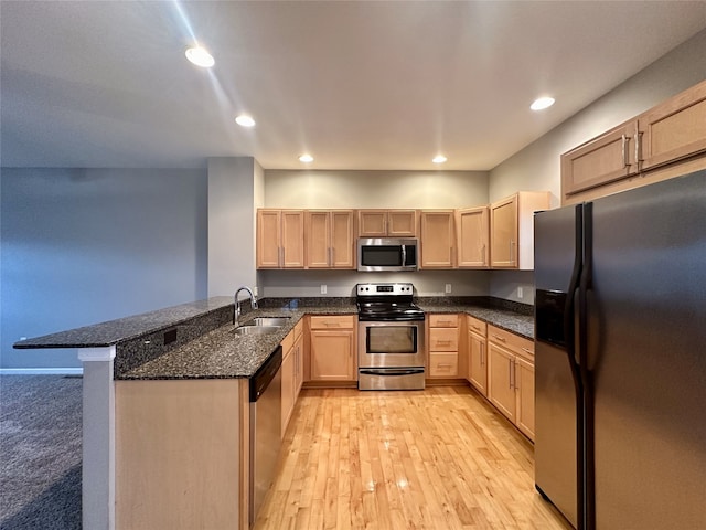 kitchen featuring kitchen peninsula, dark stone countertops, sink, light brown cabinetry, and appliances with stainless steel finishes