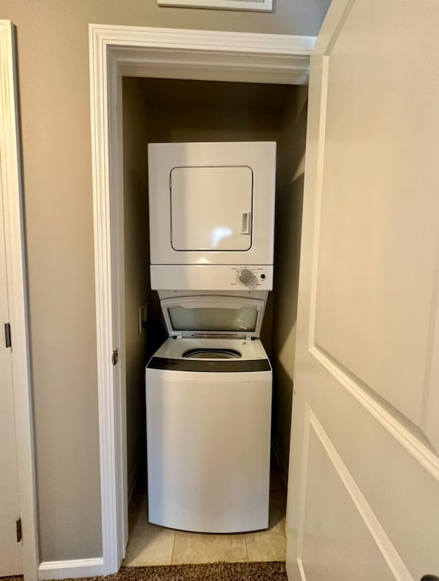 laundry area featuring stacked washer and clothes dryer and light tile patterned floors