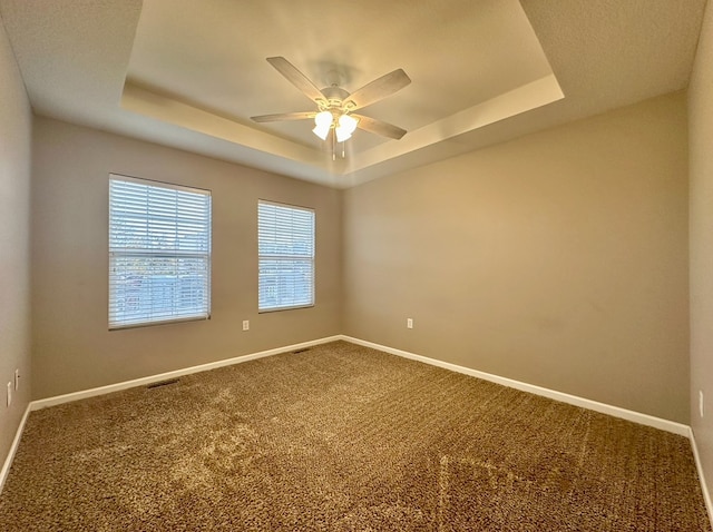 spare room featuring carpet floors, a tray ceiling, and ceiling fan