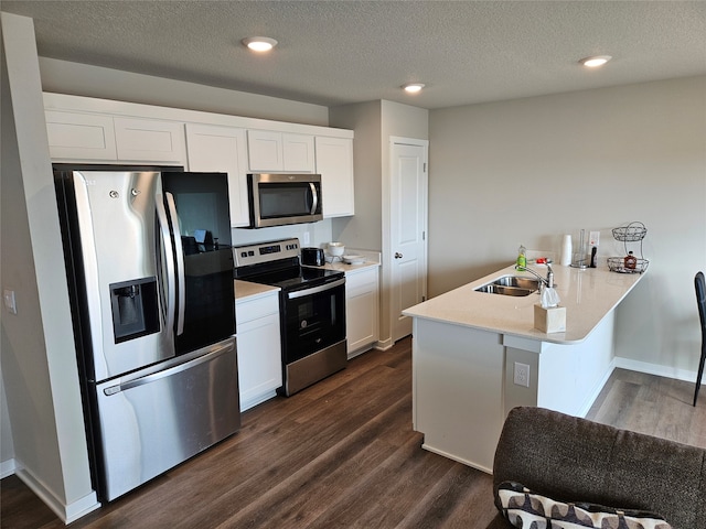 kitchen with stainless steel appliances, kitchen peninsula, dark hardwood / wood-style floors, and white cabinets