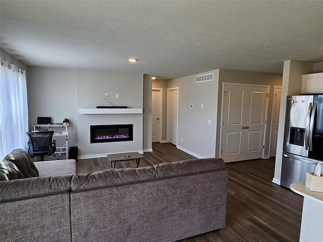 living room with a textured ceiling and dark wood-type flooring