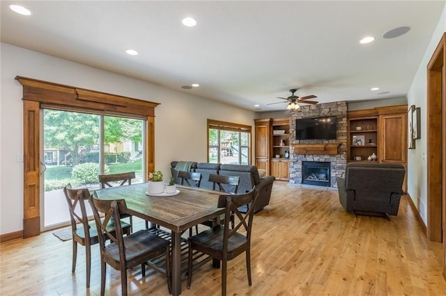 dining space featuring ceiling fan, light hardwood / wood-style flooring, and a fireplace