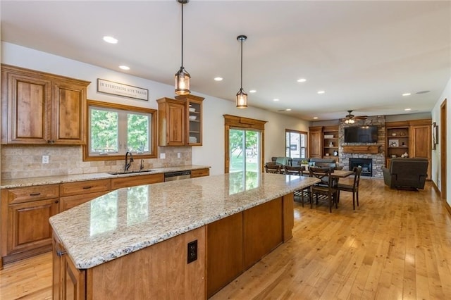 kitchen featuring sink, a fireplace, light hardwood / wood-style floors, and plenty of natural light