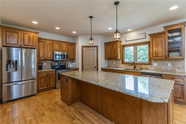 kitchen with pendant lighting, stainless steel appliances, decorative backsplash, and light wood-type flooring