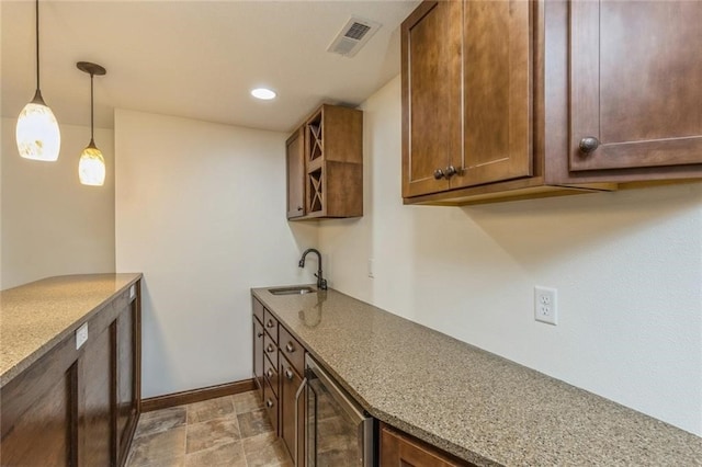 kitchen featuring beverage cooler, light stone countertops, sink, and hanging light fixtures