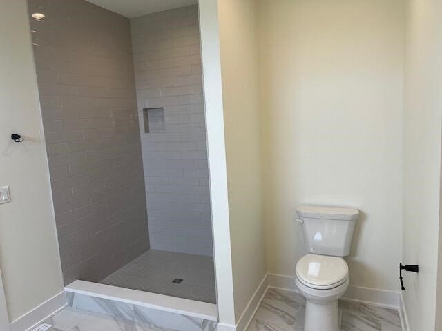 bathroom featuring toilet and a tile shower