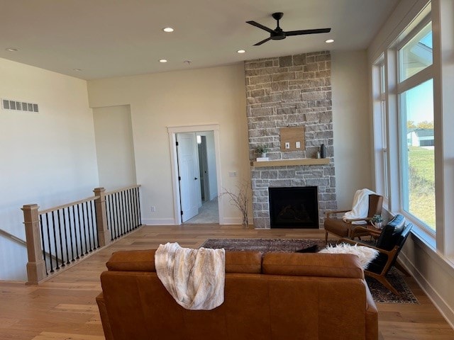 living room featuring a fireplace, ceiling fan, and light hardwood / wood-style flooring