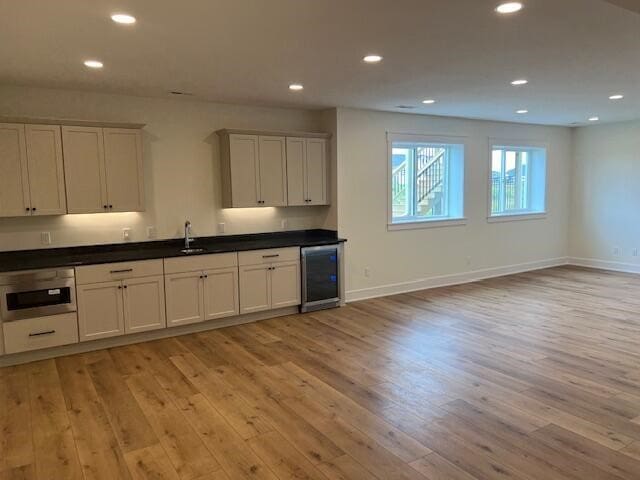 kitchen featuring white cabinetry, light hardwood / wood-style floors, sink, and wine cooler