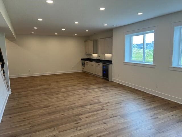 kitchen featuring white cabinetry, beverage cooler, sink, and light hardwood / wood-style floors