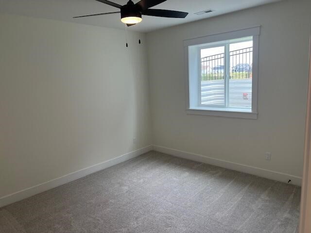 carpeted spare room featuring ceiling fan