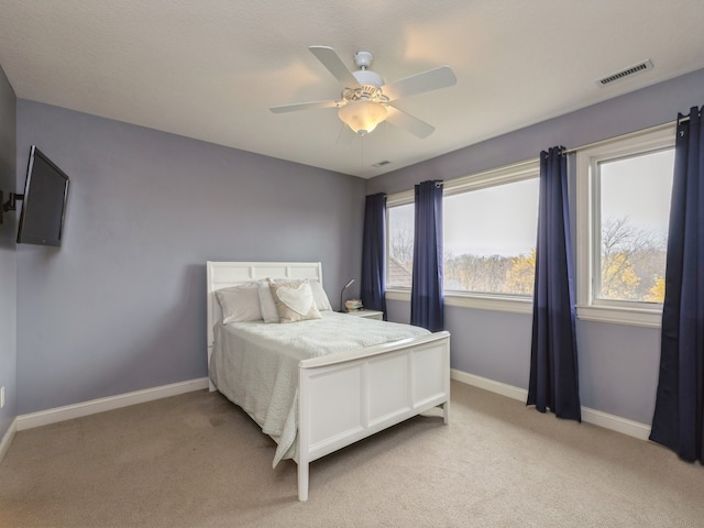 bedroom featuring light carpet, ceiling fan, visible vents, and baseboards