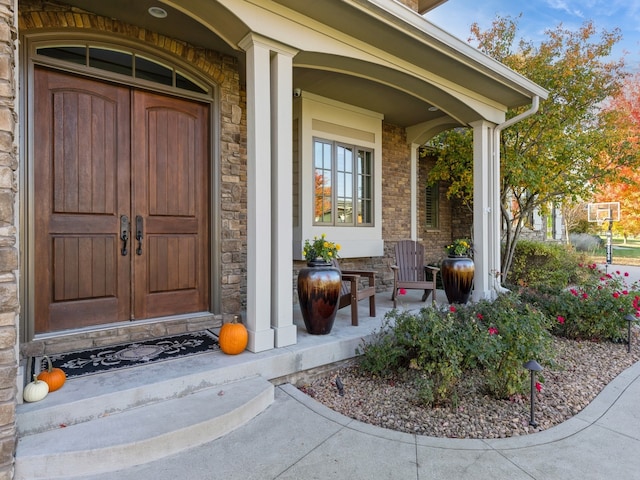 view of exterior entry featuring covered porch and stone siding