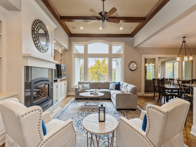 living area with beamed ceiling, a healthy amount of sunlight, a premium fireplace, and light wood-style floors