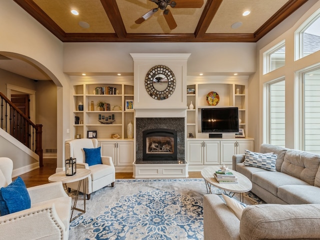 living room featuring coffered ceiling, light wood-style flooring, baseboards, and a premium fireplace